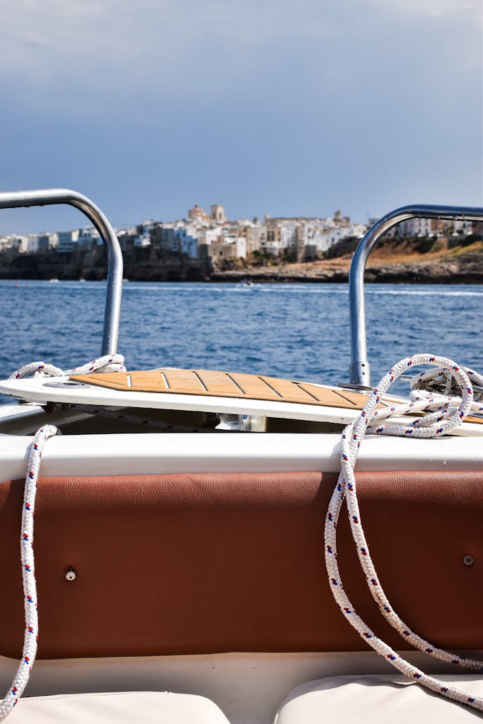 Scenic boat view of Polignano a Mare's rocky coastline in Apulia, Italy, under a clear blue sky.